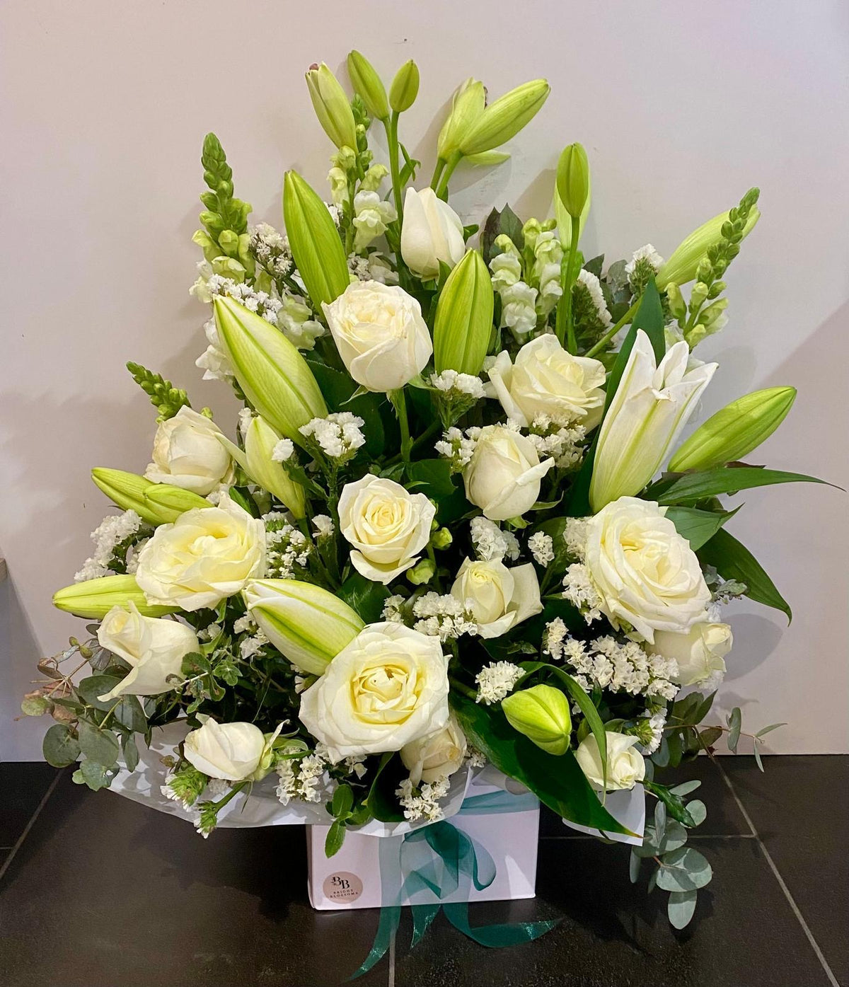 Pure Elegance Box featuring white roses, oriental lilies and snapdragons arranged with seasonal filler flowers and fresh foliage in a premium square gift box.