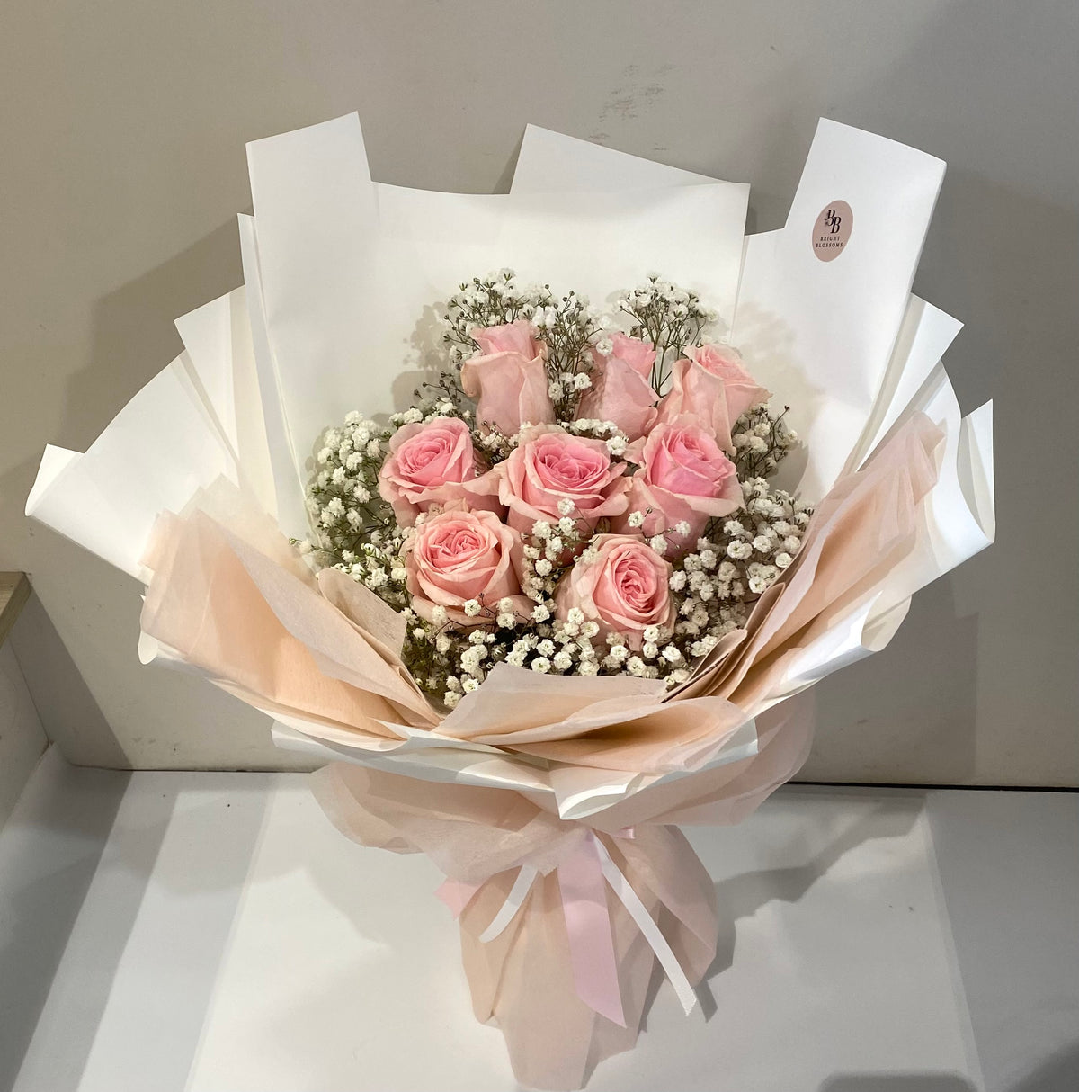 8 premium long‑stem pink roses paired with fresh baby’s breath, wrapped in elegant premium paper