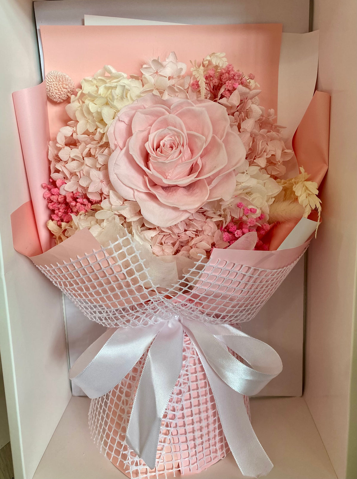 Everlasting preserved flower bouquet in soft pink tones featuring long‑lasting dried blooms arranged in a clear display box.