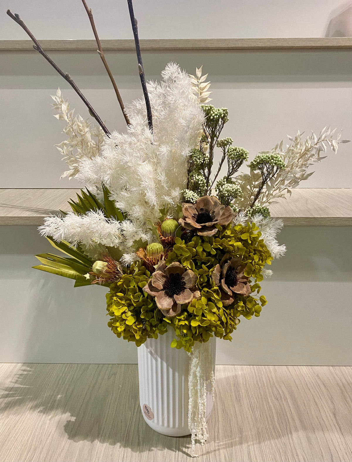 Dried and preserved flower arrangement in soft white and green tones displayed in a modern vase, featuring natural textures and long‑lasting blooms