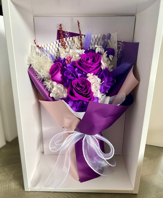Everlasting preserved flower bouquet in soft purple tones featuring long‑lasting dried blooms arranged in a clear display box
