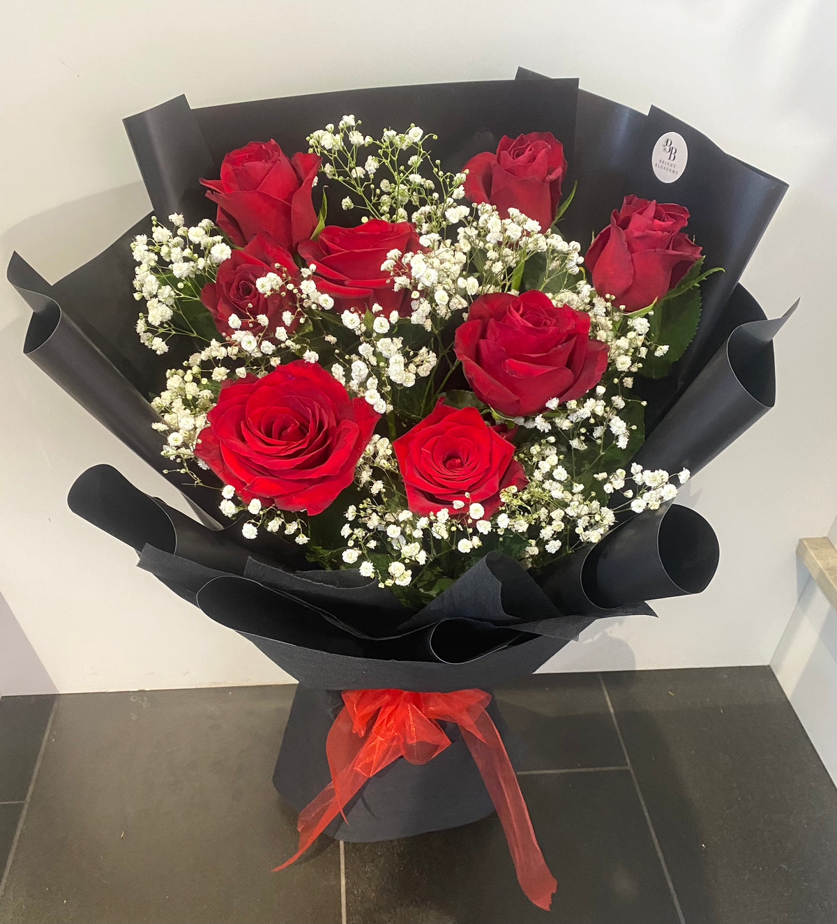 8 premium long‑stem red roses paired with fresh baby’s breath, wrapped in elegant premium paper.