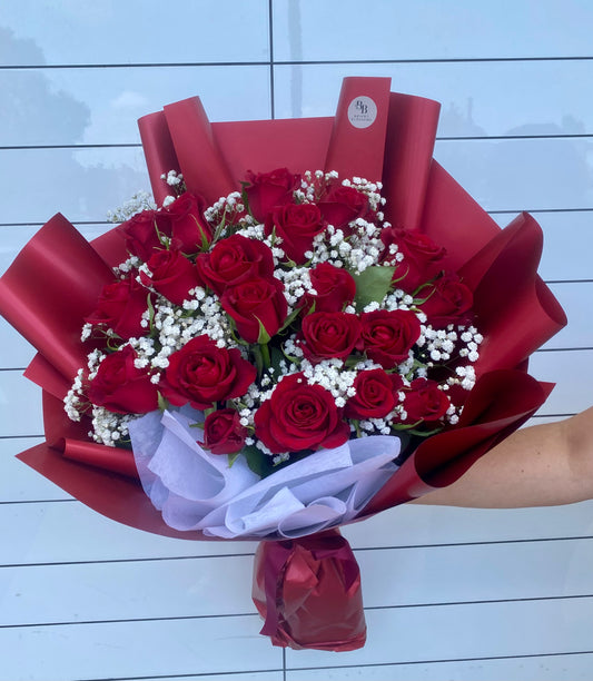 24 premium long‑stem red roses paired with fresh baby’s breath, wrapped in elegant premium paper for a timeless romantic bouquet.