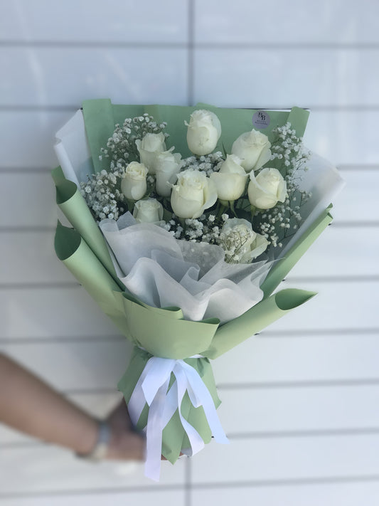 10 premium long‑stem white roses paired with fresh baby’s breath, wrapped in elegant premium paper.